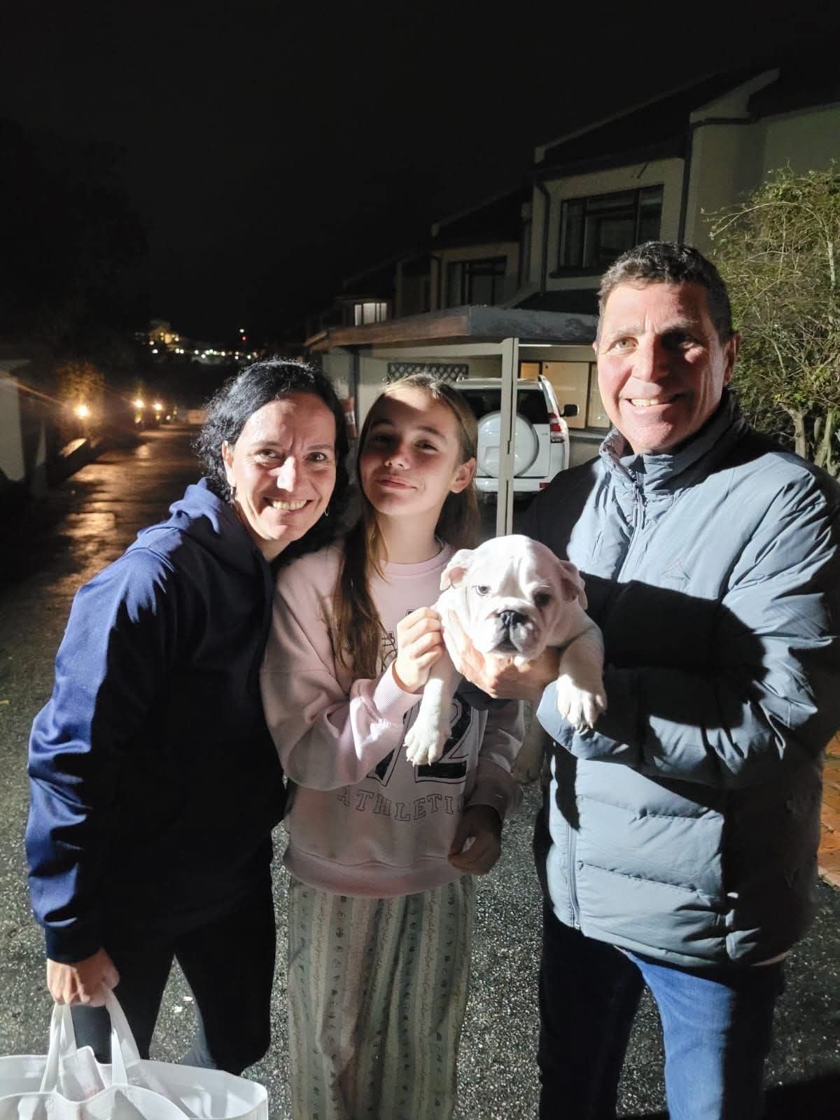 A family meeting their puppy at the end of a long evening drive