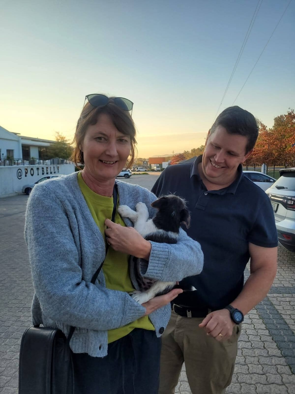 A couple at sunset with their black and white puppy