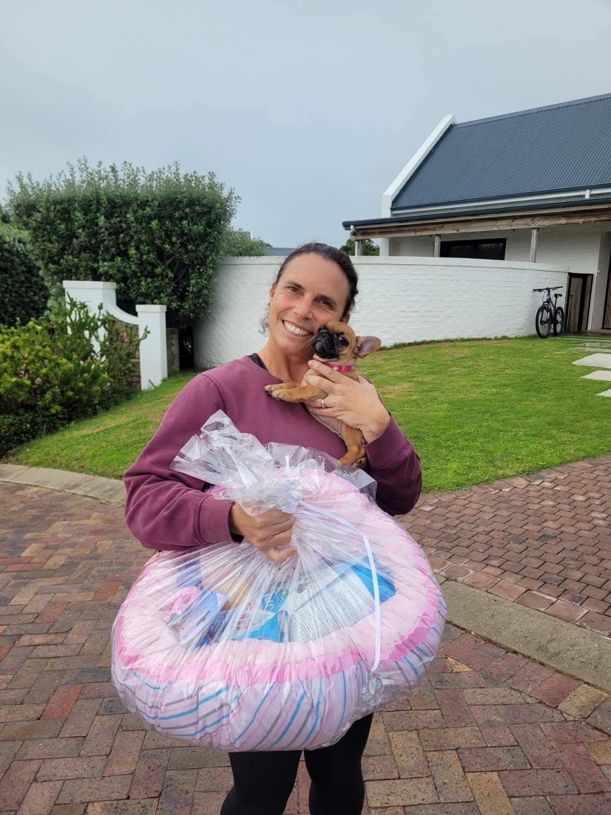 A woman with her puppy and a gift bag from the breeder