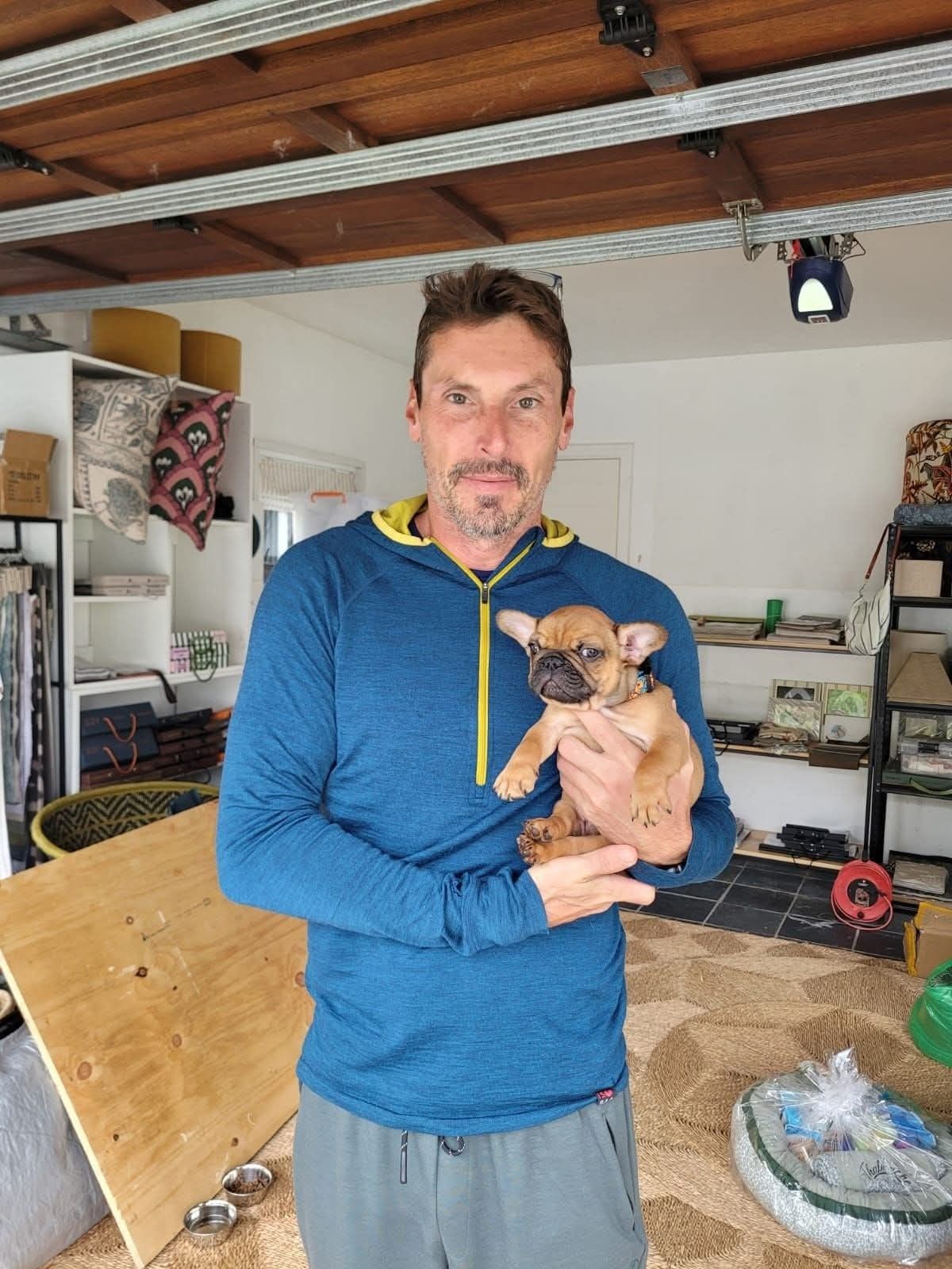 A man with his tan puppy at home in the garage