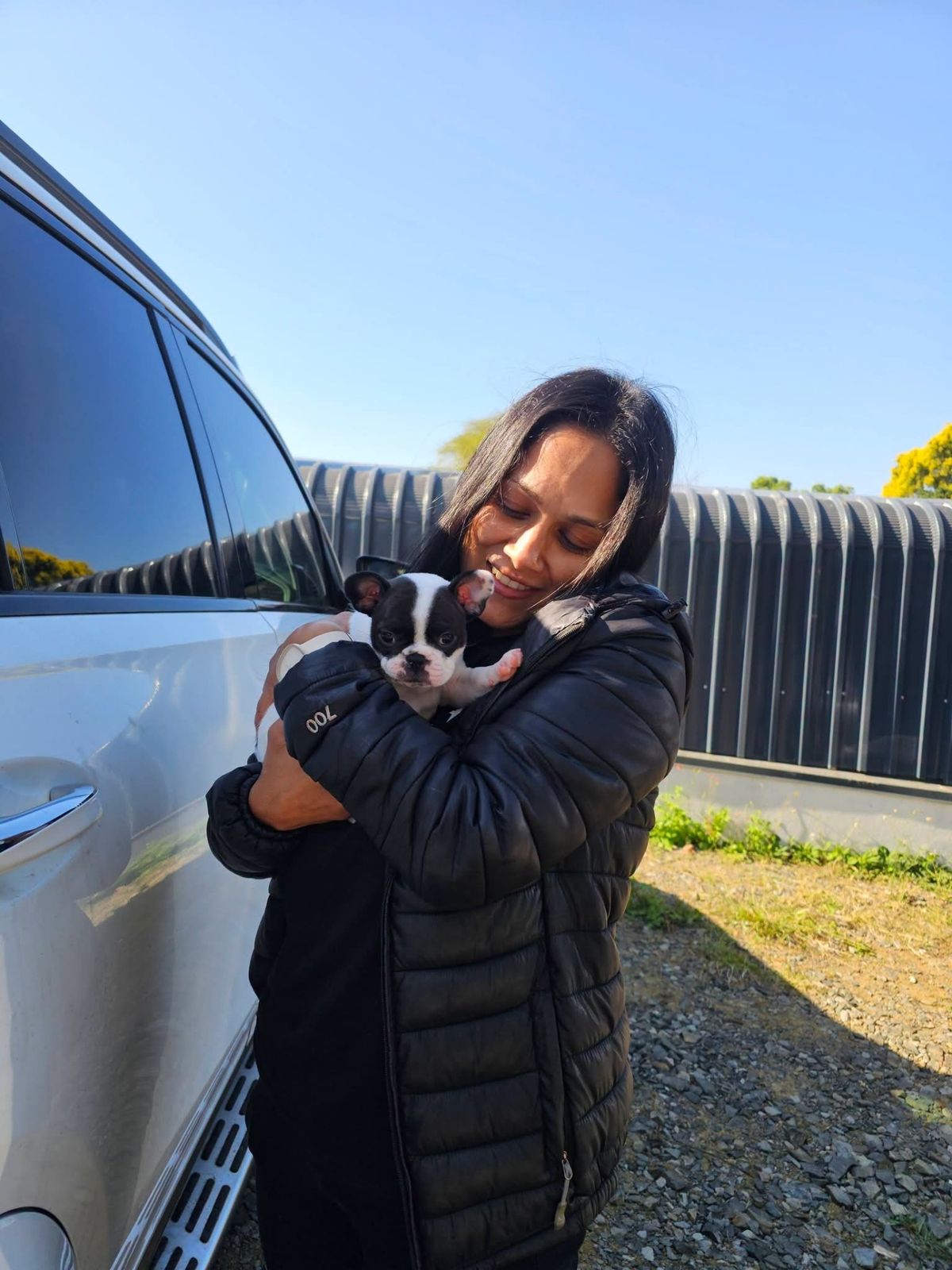 A new owner holding her black and white puppy close