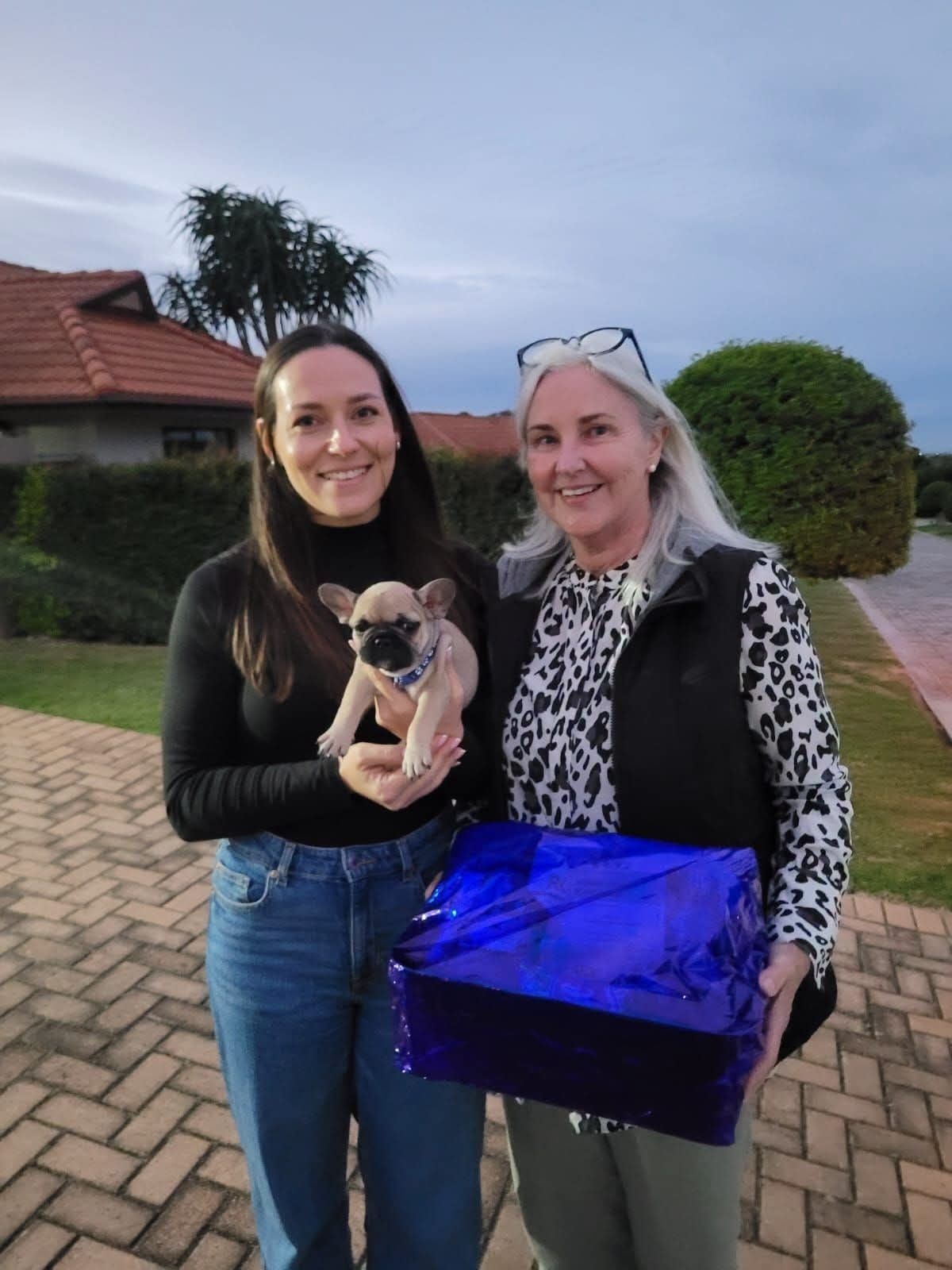 Two friends collecting a puppy with a gift bag