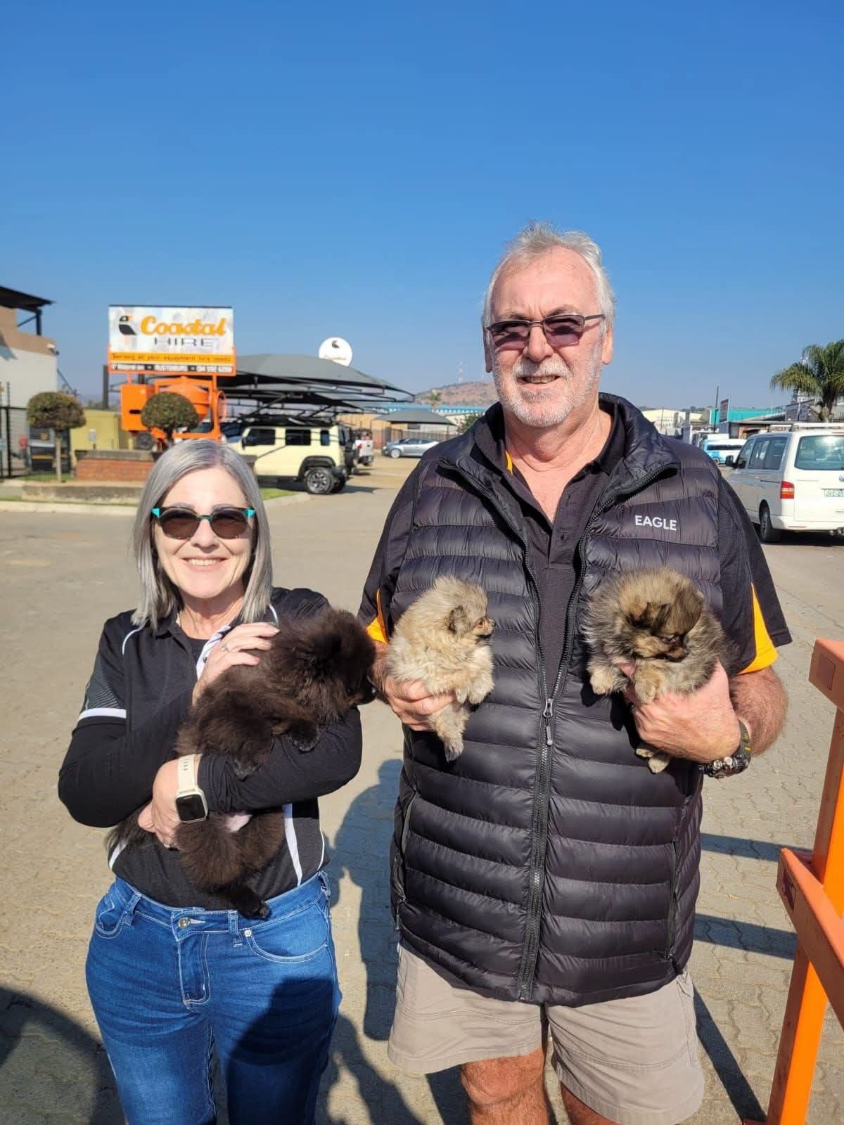 A pair of new owners at a filling station, a puppy each