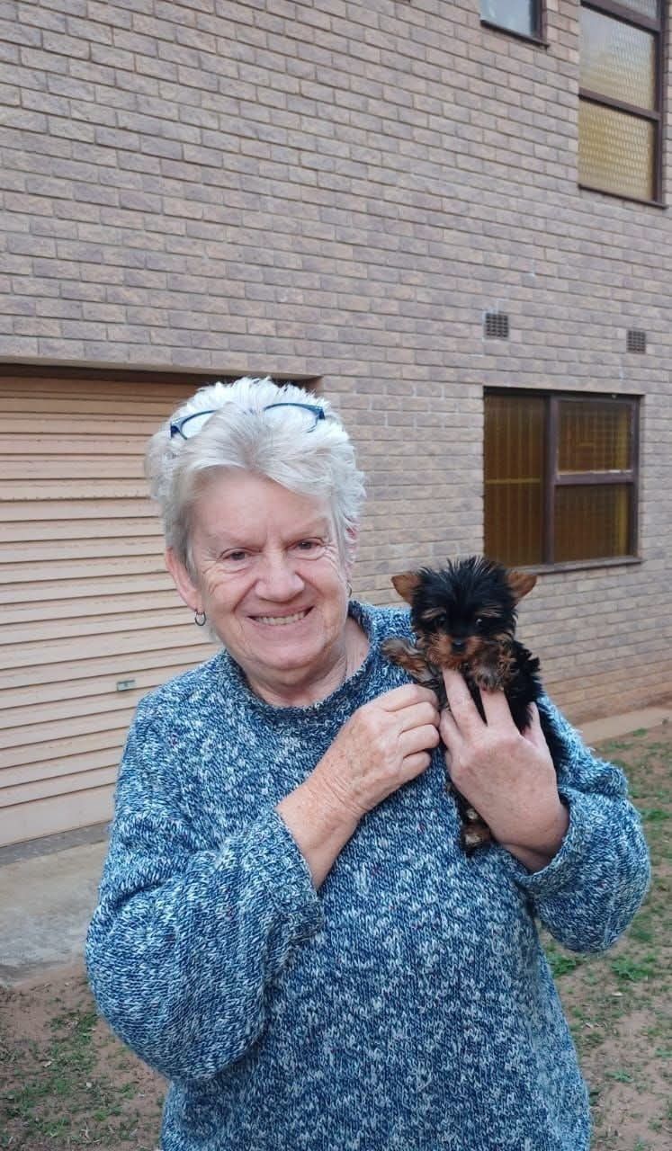 An older woman meeting her tiny black puppy at home