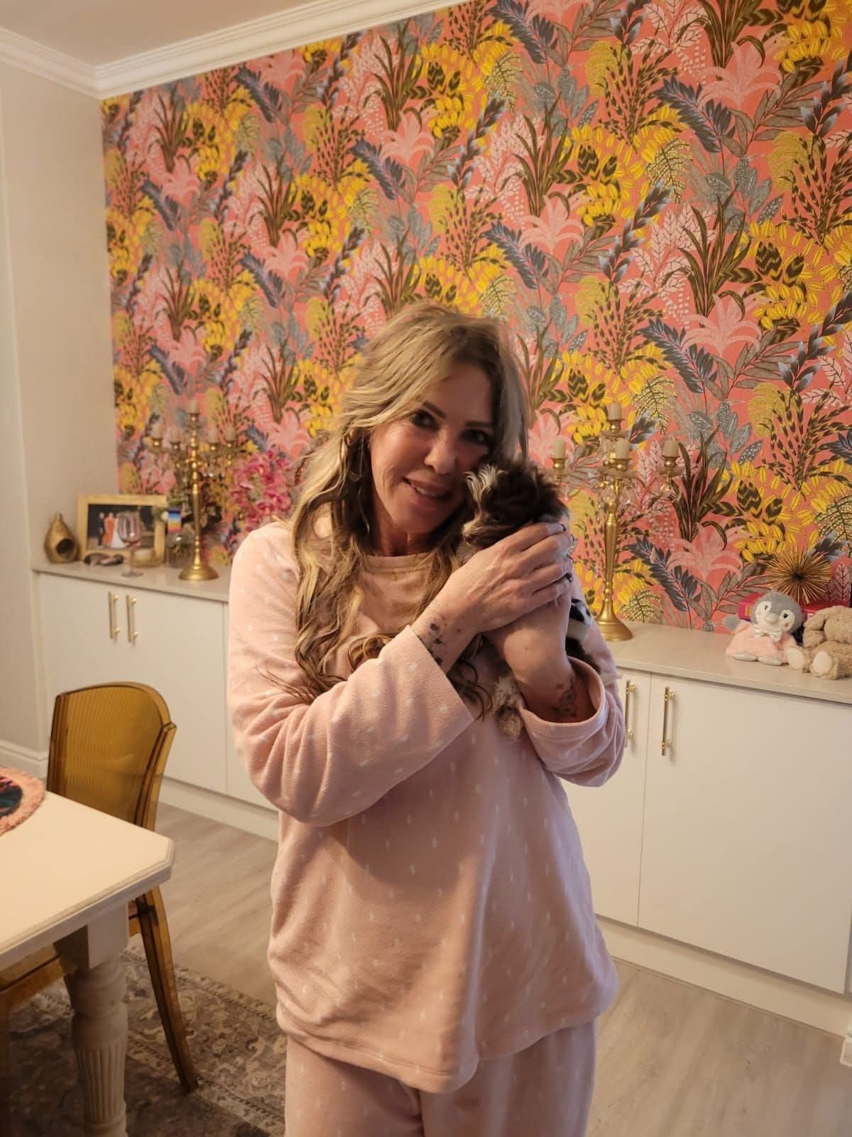 A new owner indoors with her small dark puppy